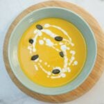 Crema de Auyama Dominicana en un bol con nata y guarnici&oacute;n de semillas de calabaza.