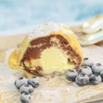 A cross-section view of the Fried Ice Cream in marble bread with blueberries around it.