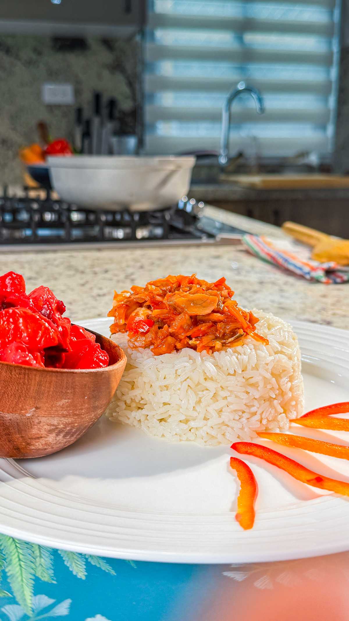 Bacalao guisado served over white rice with red peppers on the side.