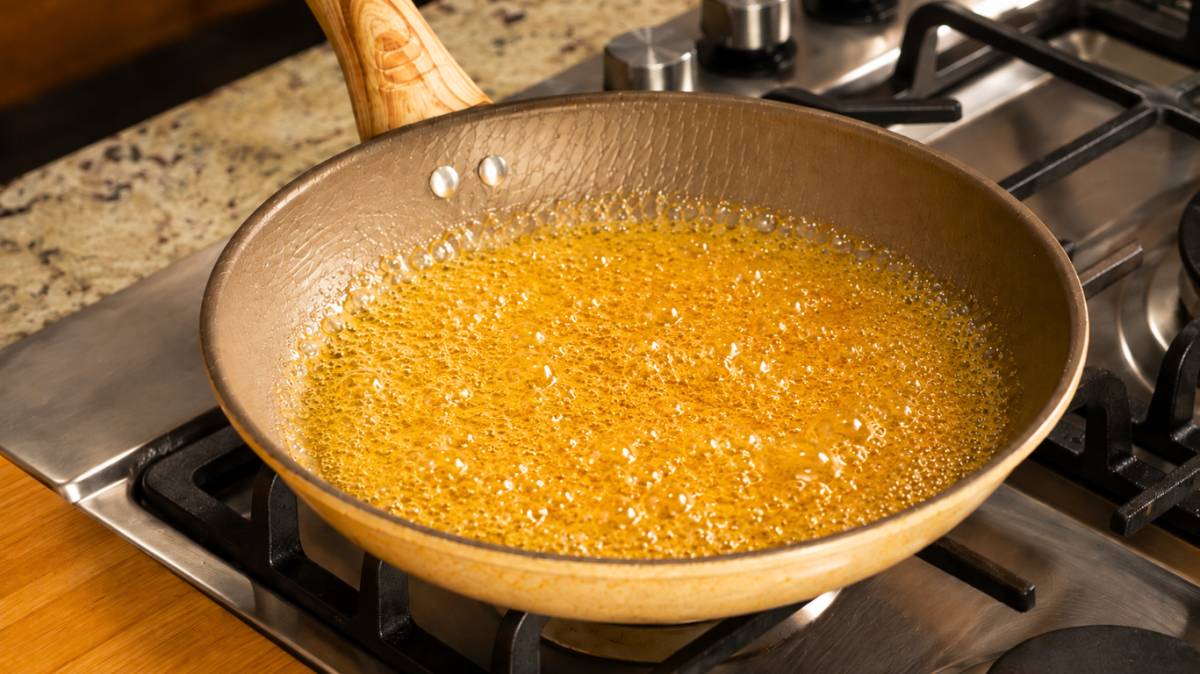Golden caramel bubbling in a pan for Venezuelan quesillo
