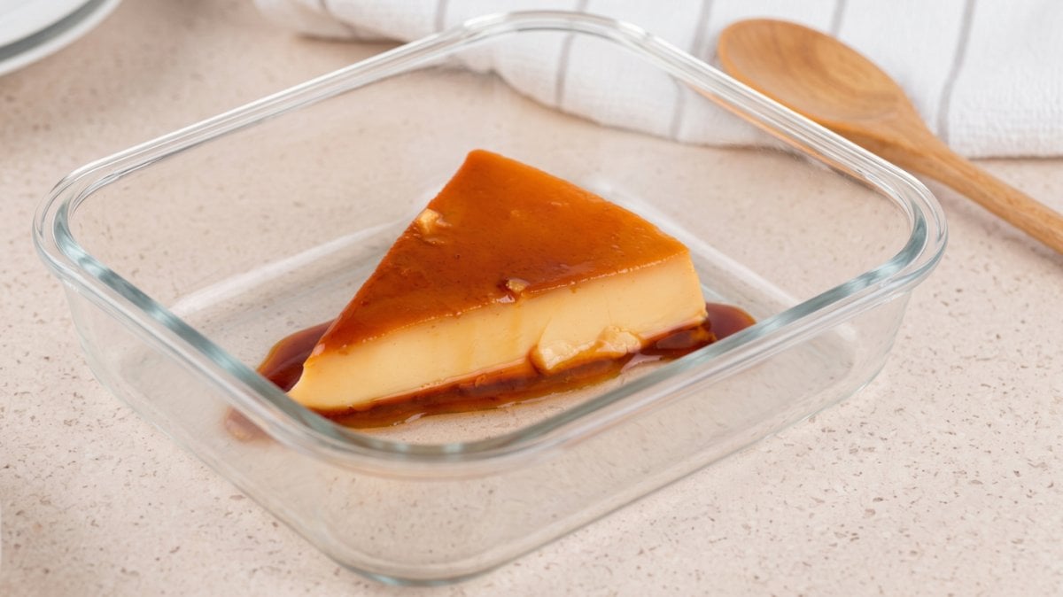 Slice of creamy Venezuelan quesillo with caramel sauce in a glass container