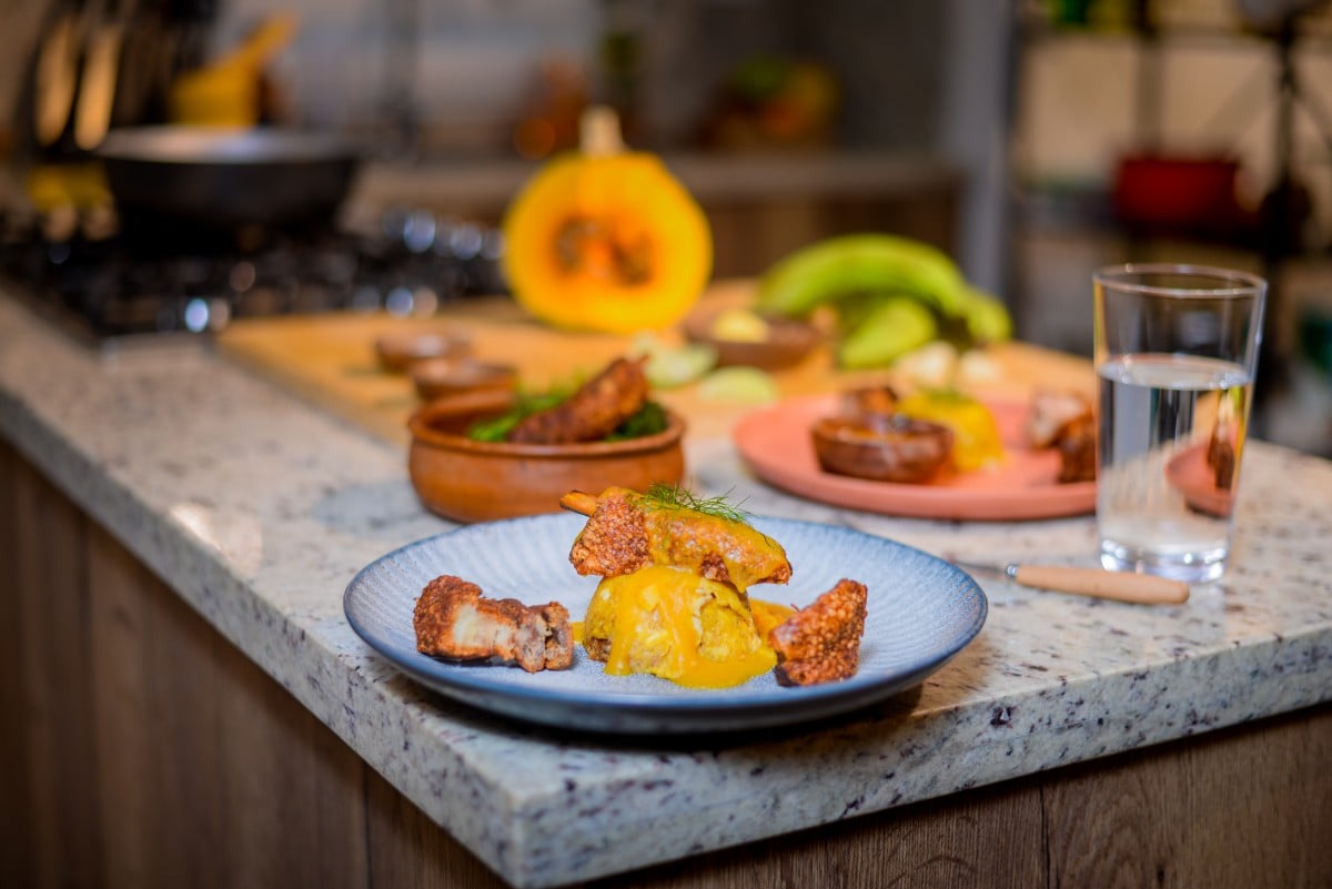 Dominican mofongo con chicharrón served with crema de auyama in a kitchen setting